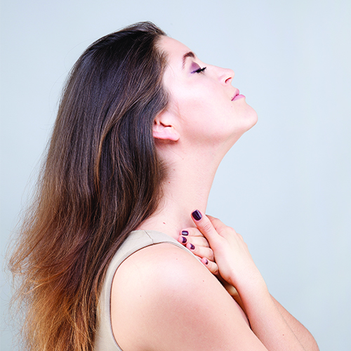 A woman stretching her neck by using her fingertips to massage the base of her neck