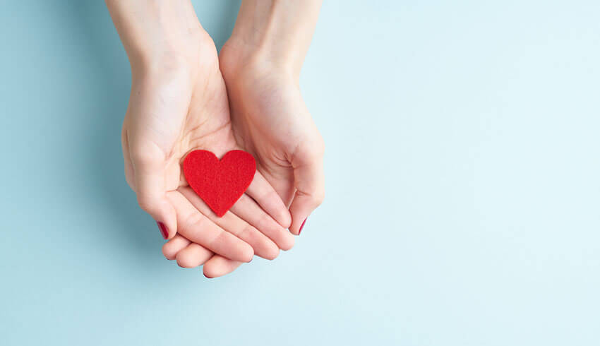 Two overlapping hands display a red felt heart