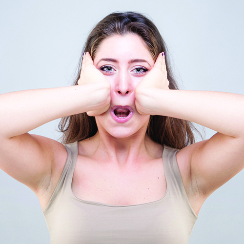 A woman using the palms of her hands to massage the center of her face above her mouth