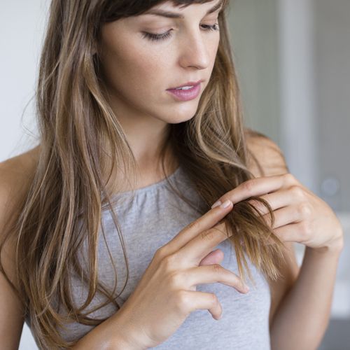 A woman looking at the ends of hair