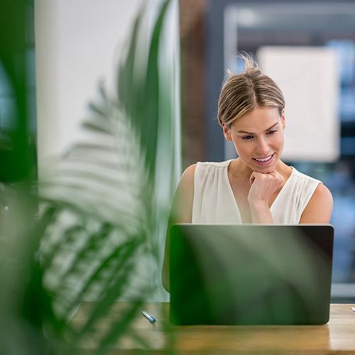 Woman working on lap top at a front desk.