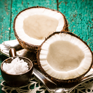 A coconut split in half sits next to a container of coconut shavings