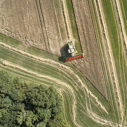 A bird's-eye view of farm equipment driving in a field