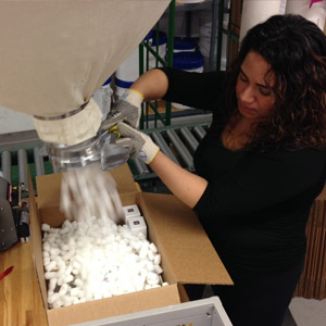 A woman filling a box with Styrofoam packing peanuts.