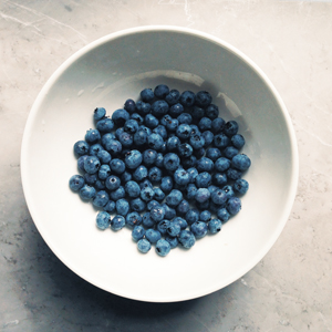 The top view of fresh blueberries displayed inside a white bowl.