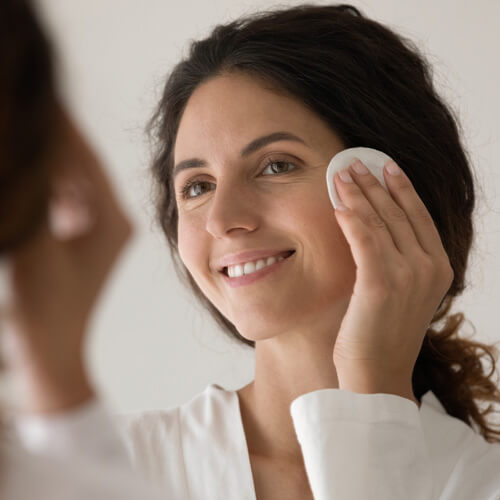 A woman padding face with cotton