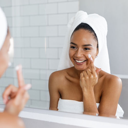 A woman putting cream on her cheek