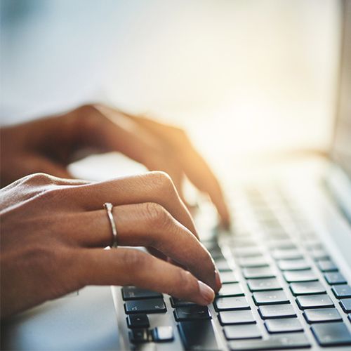 A close-up of a woman's hands typing on a keyboard