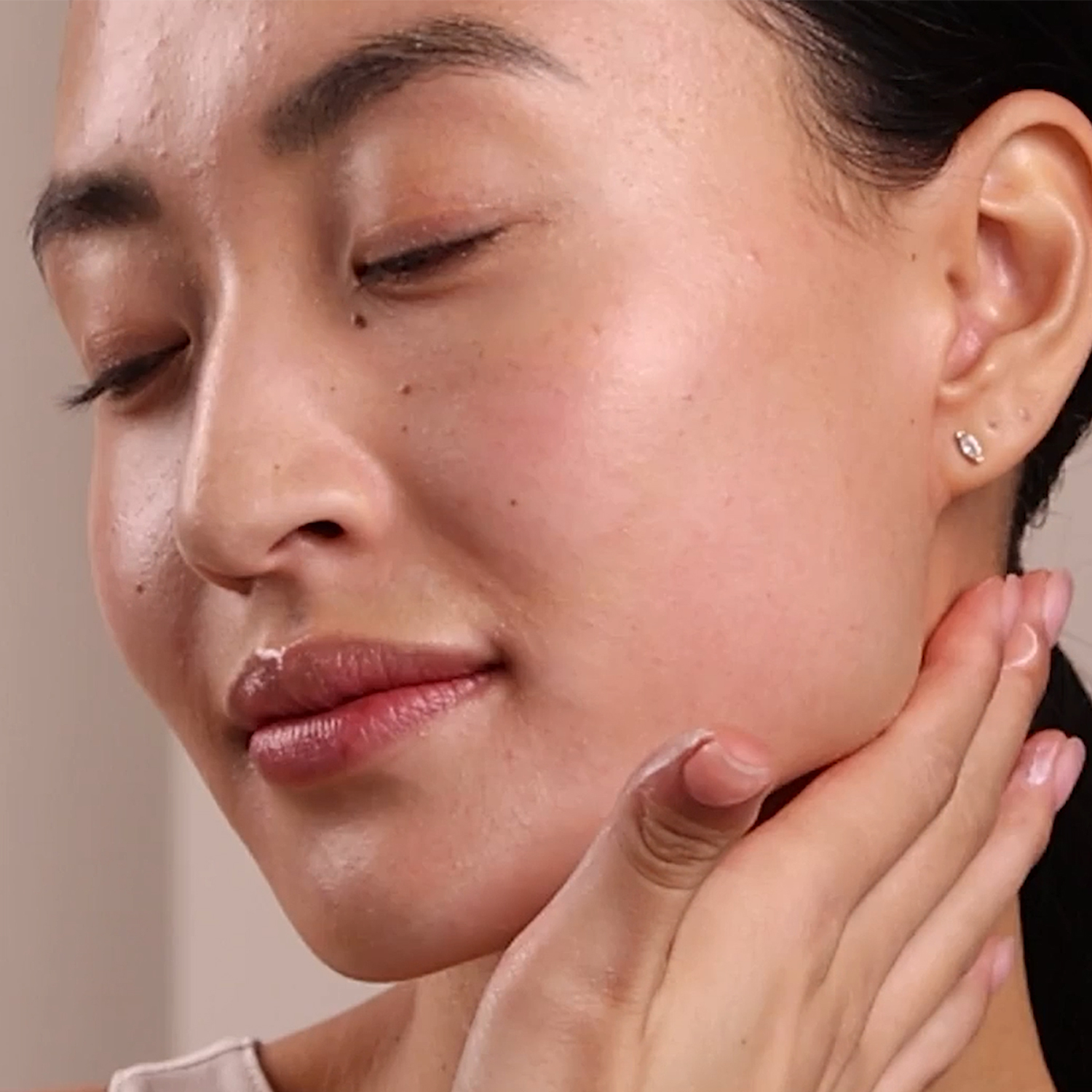 A woman applying the Eminence Organics Monoi Age Corrective Night Cream for Face & Neck to her neck