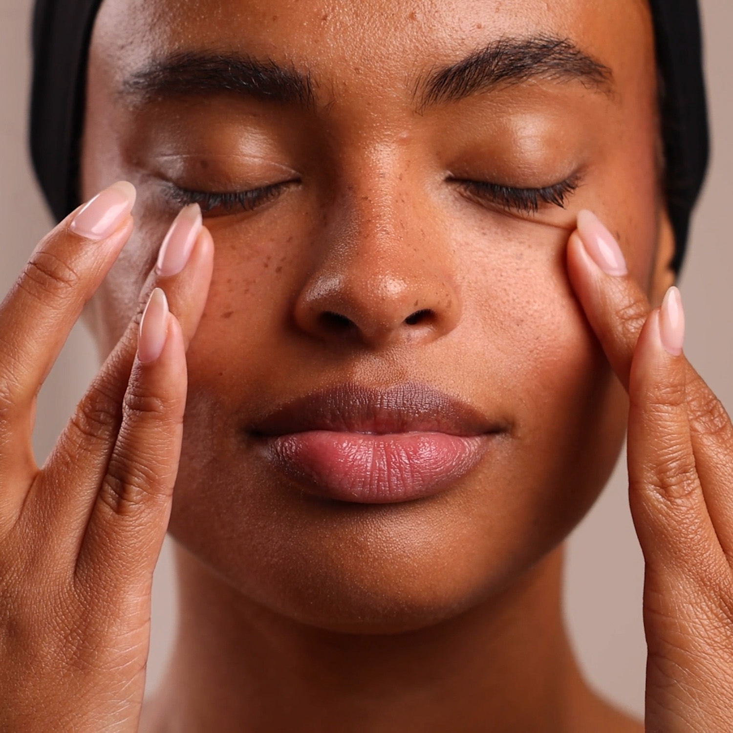 A woman applying the Eminence Organics Neroli Age Corrective Eye Serum to the eye area