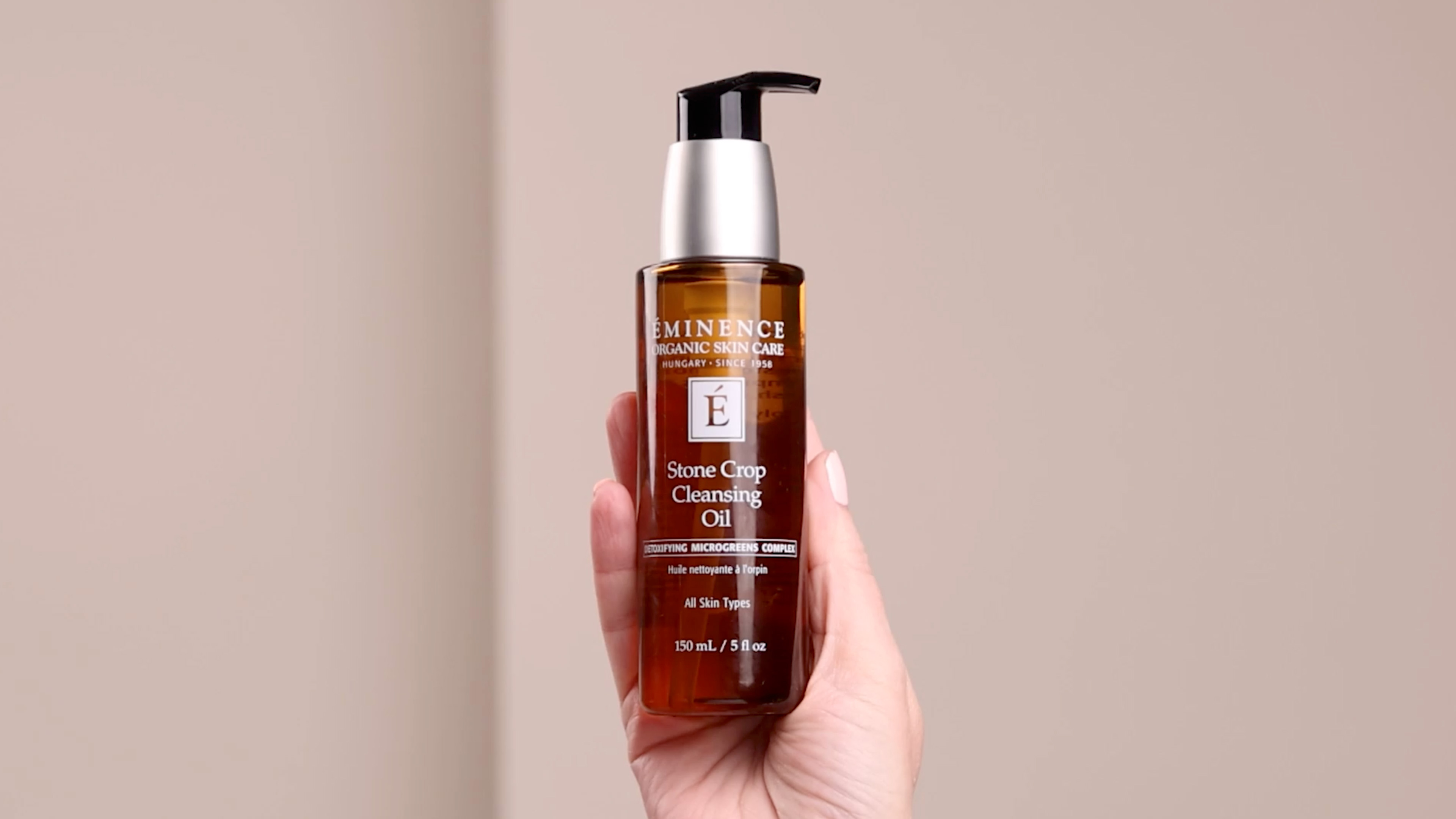 A hand holding the Eminence Organics Stone Crop Cleansing Oil